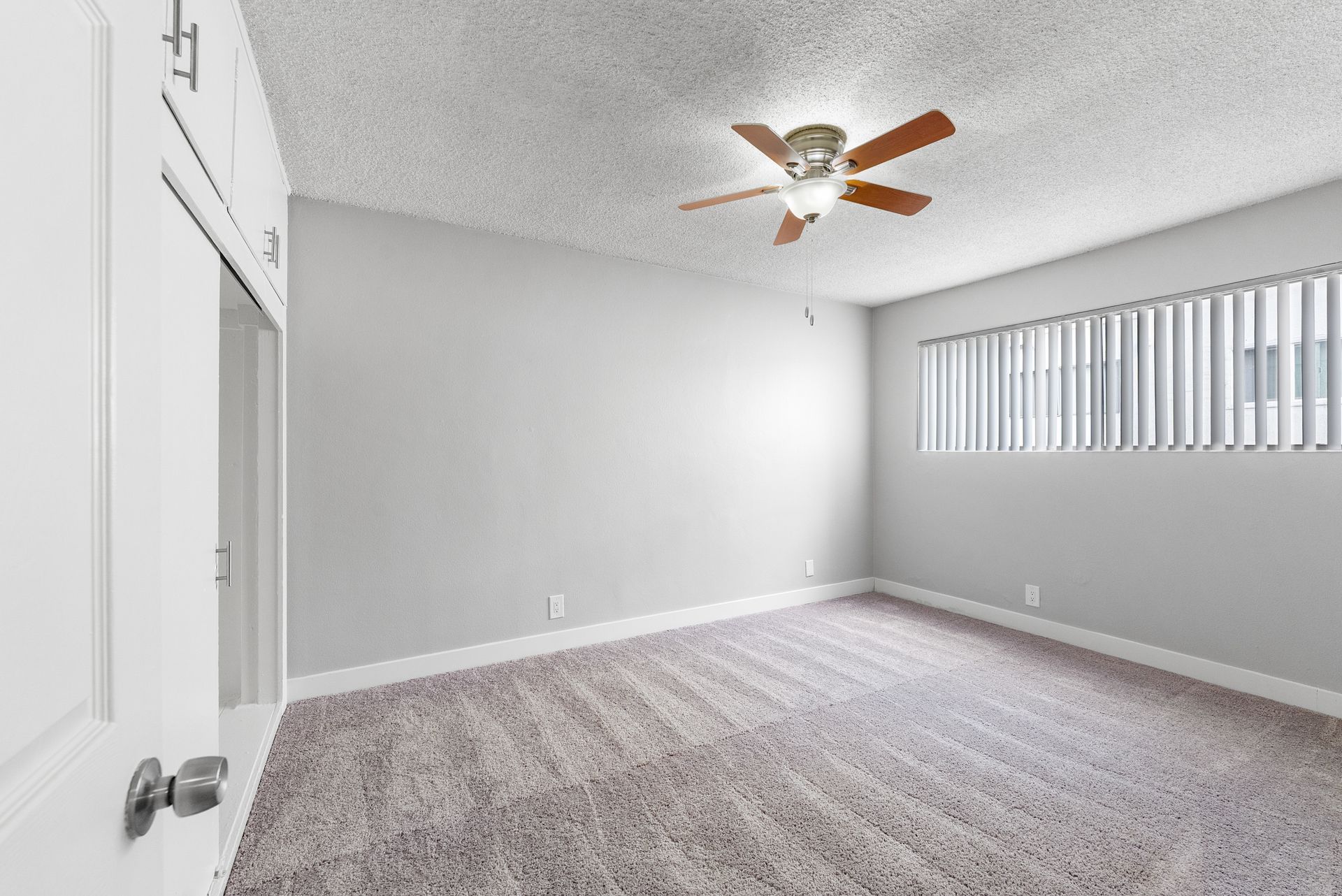 carpated bedroom with window and fan