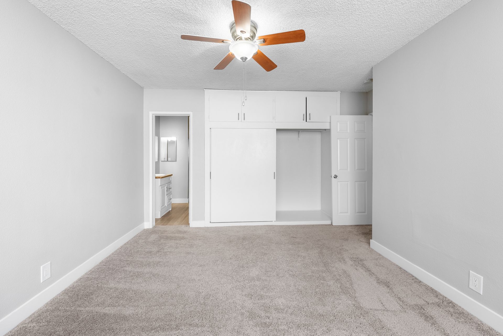 carpeted bedroom with closet and open door to restroom
