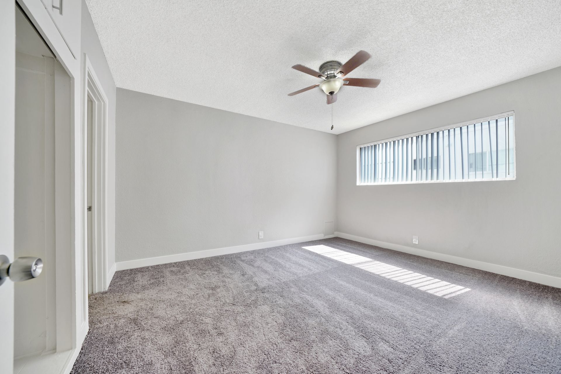 Photo of a carpeted bedroom, with a ceiling fan