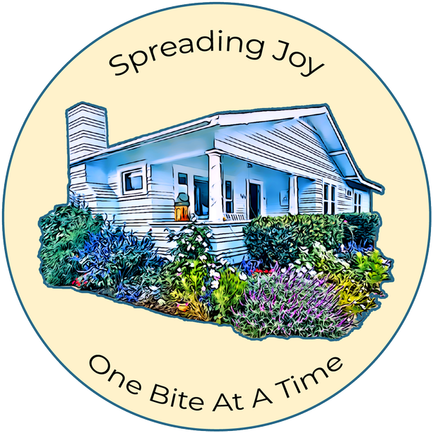 Blue Cottage Bakery logo of a blue house with flowers, surrounded by text “Spreading Joy” and “One Bite At A Time”