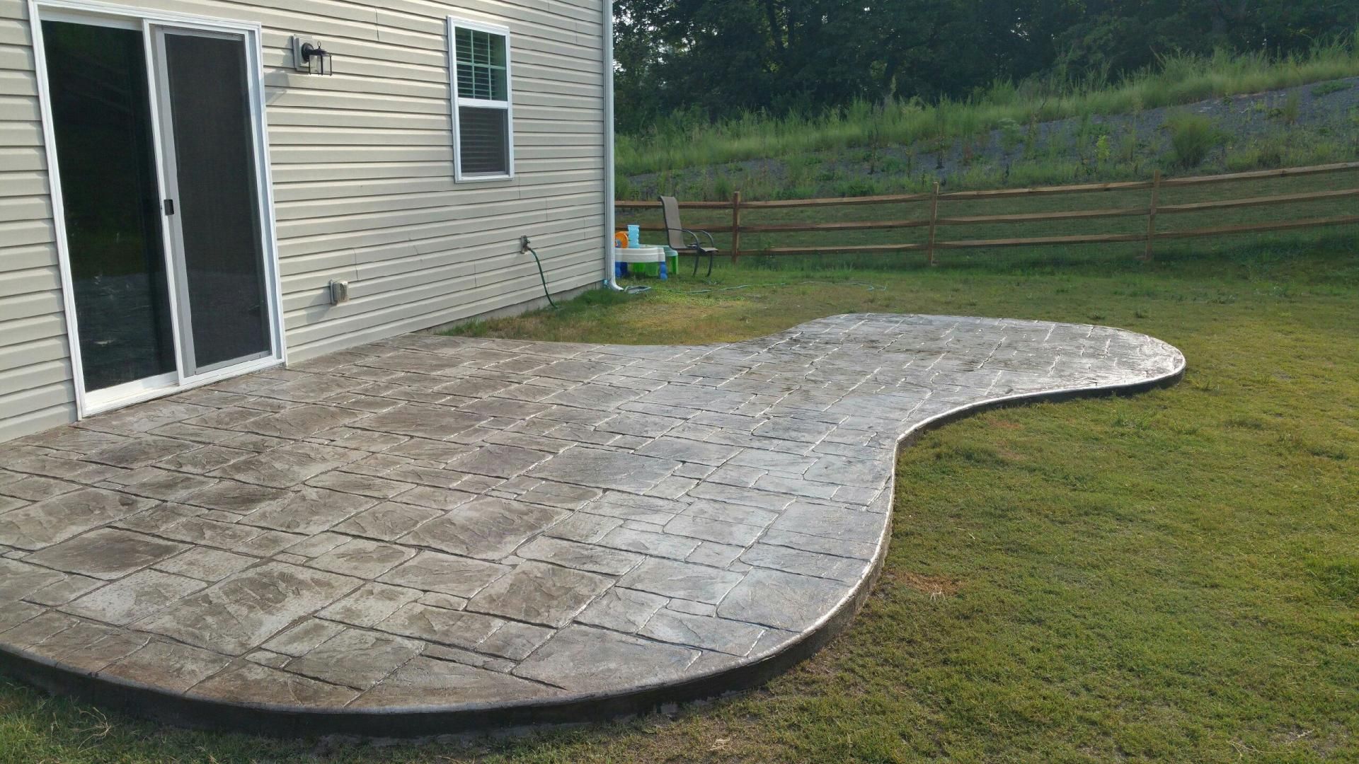 A concrete patio in the backyard of a house.