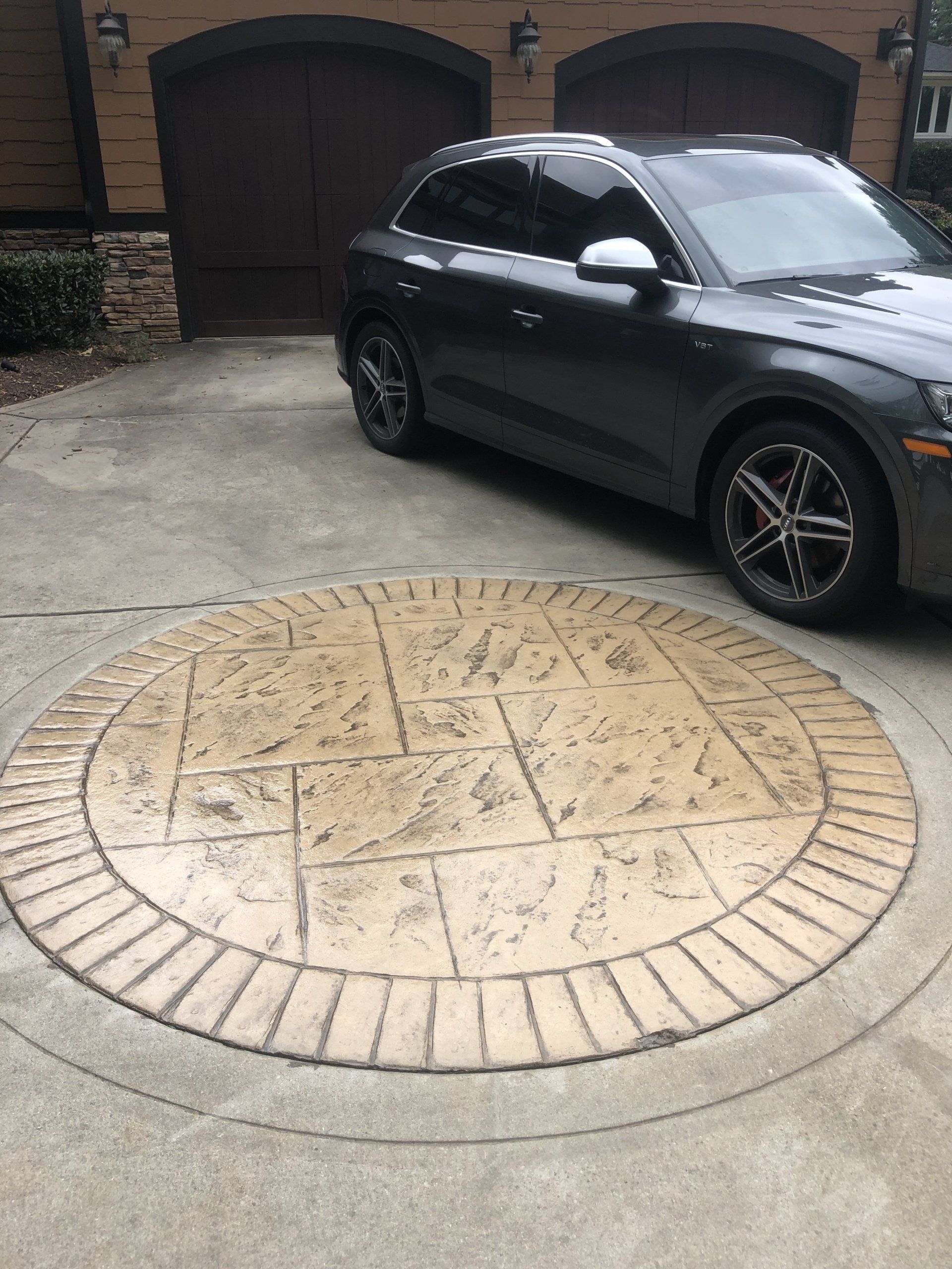 A car is parked in a driveway in front of a garage.
