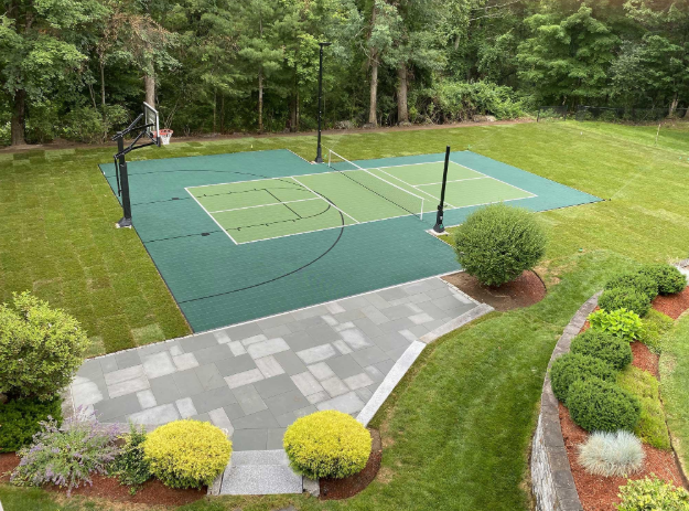 “Backyard multi-sport court with green and blue playing areas surrounded by lawn and trees after a court builder service in Henderson, NV”