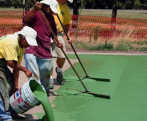 “Crew pouring and spreading green court coating evenly across a sport surface during a court builder service in Henderson, NV”