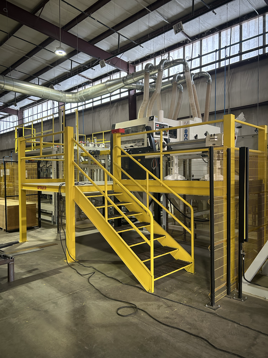 Yellow industrial machine with stairs and platform inside a factory warehouse