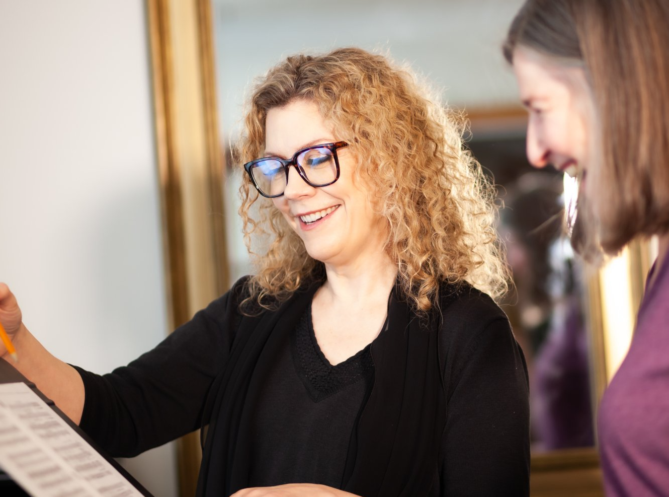 Two women are standing next to each other looking at a piece of paper.