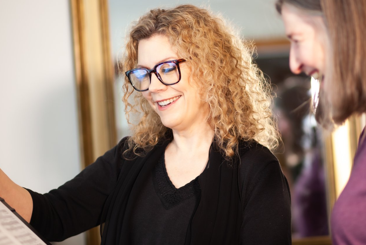A woman wearing glasses is talking to a man in front of a mirror.