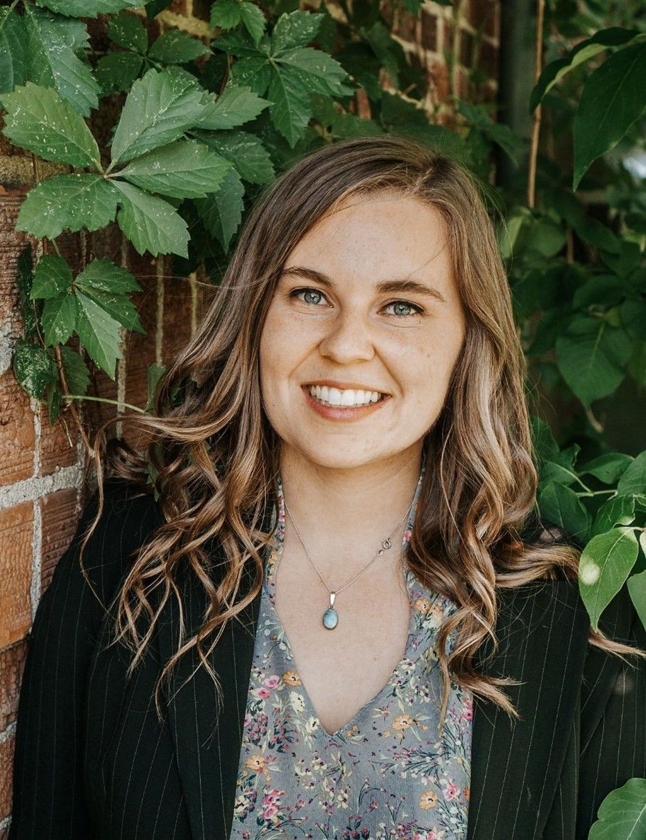A woman is smiling for the camera while standing in front of a brick wall.