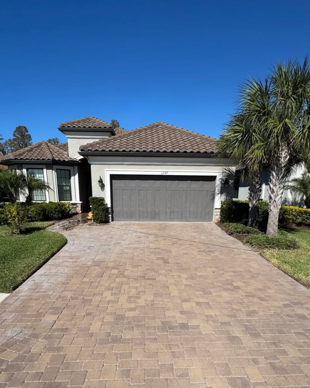 A light grey paver patio edge bordered by mulch, a potted plant, and outdoor solar lights under dappled tree shadows.