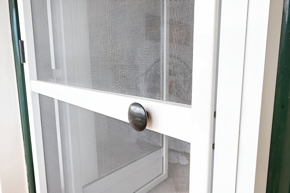 A Close Up of a White Screen Door With a Black Handle — Manning Blinds & Awnings in Hallidays Point, NSW