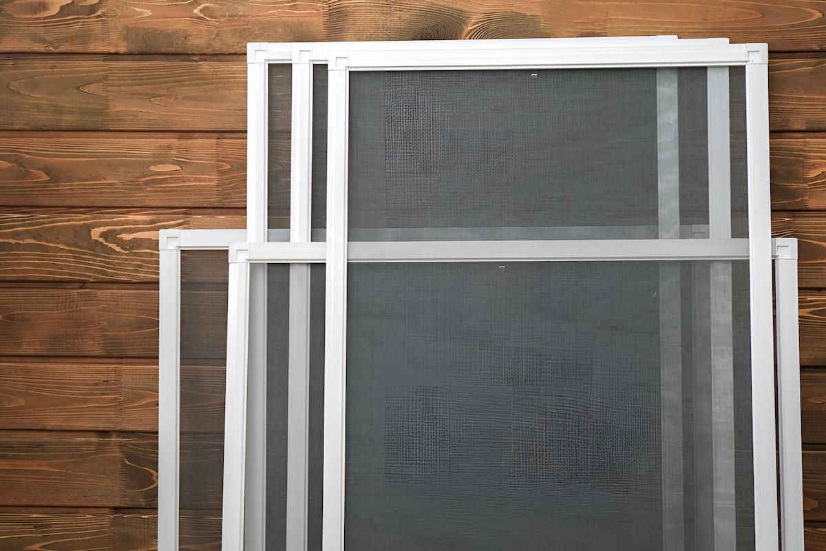 A Stack of Mosquito Screens Sitting on Top of Each Other on a Wooden Wall — Manning Blinds & Awnings in Taree, NSW