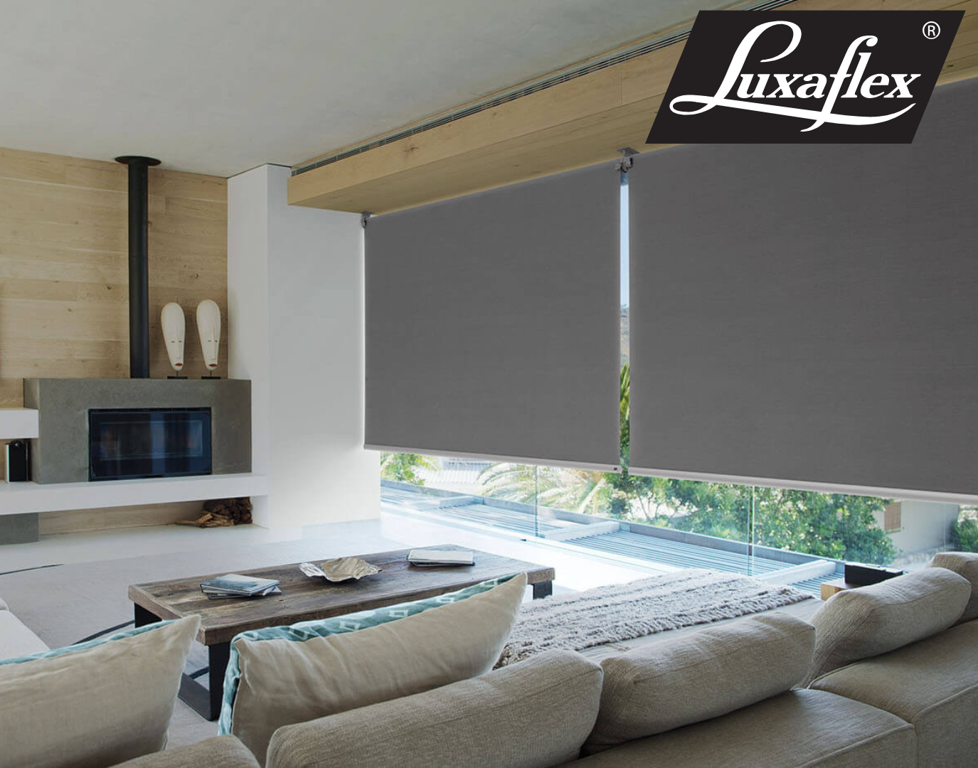 Window seat with a gray cushion and pillow, a closed gray roller shade, and a view of green trees — Manning Blinds & Awnings in Taree, NSW