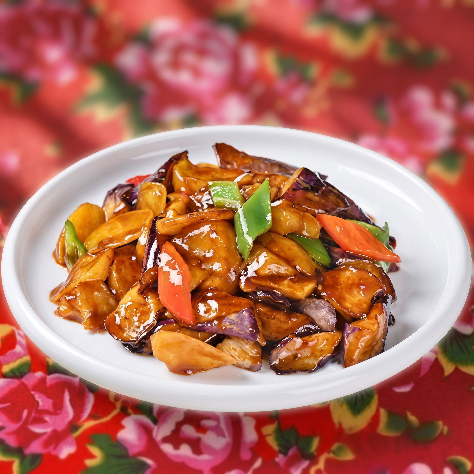 White bowl of glazed stir-fried vegetables on a red floral tablecloth