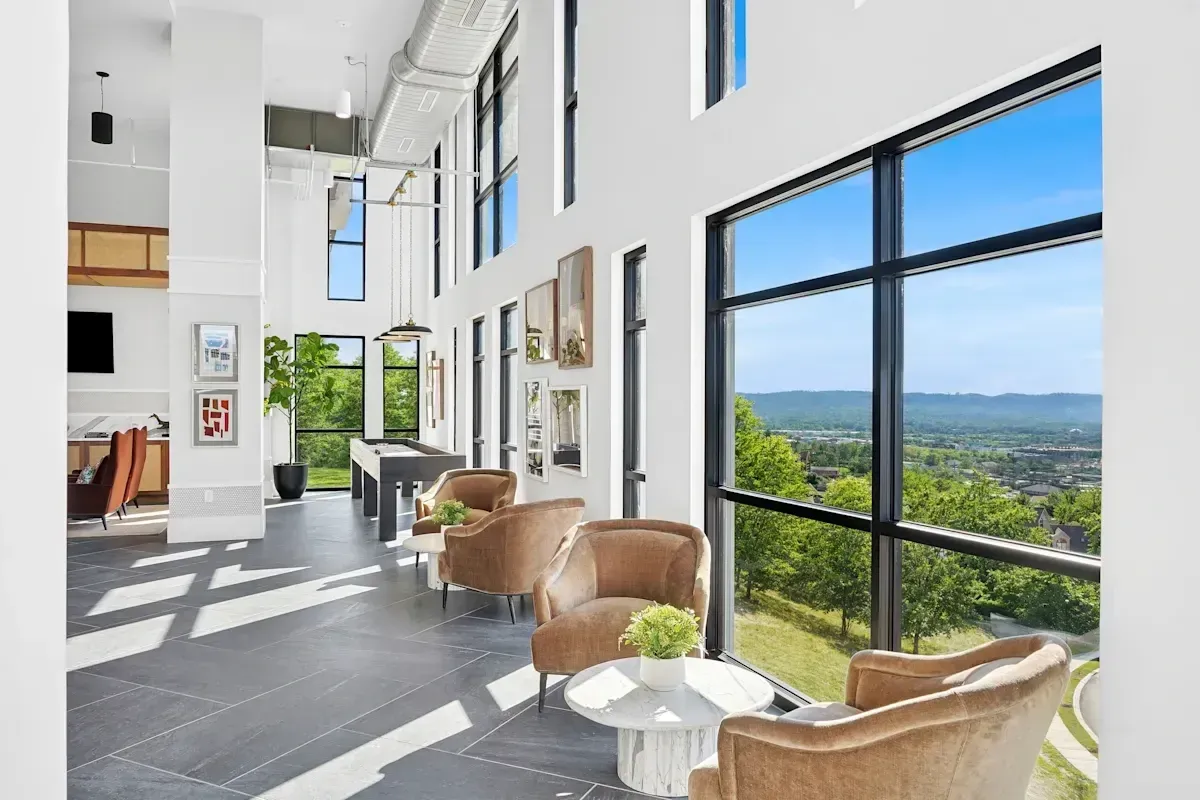 Modern lounge area with plush armchairs, a pool table, and large windows offering scenic views.
