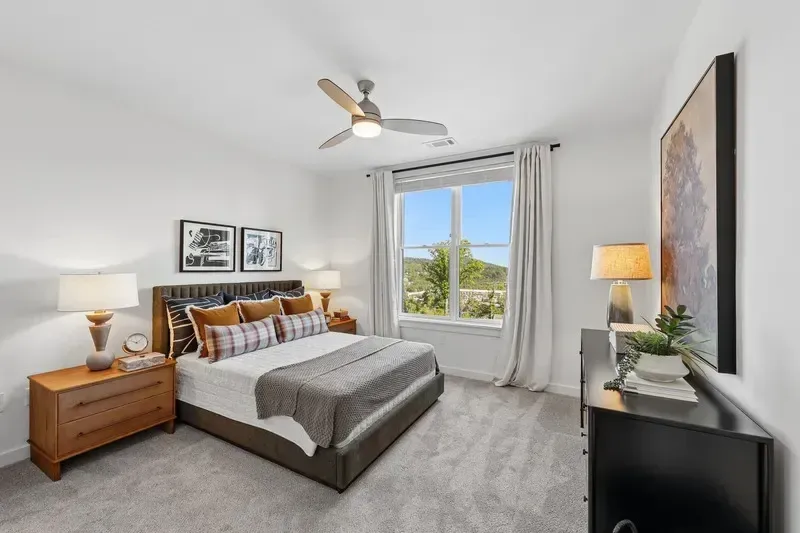 Bedroom with a king-size bed, nightstands, dresser, and large window with a view.