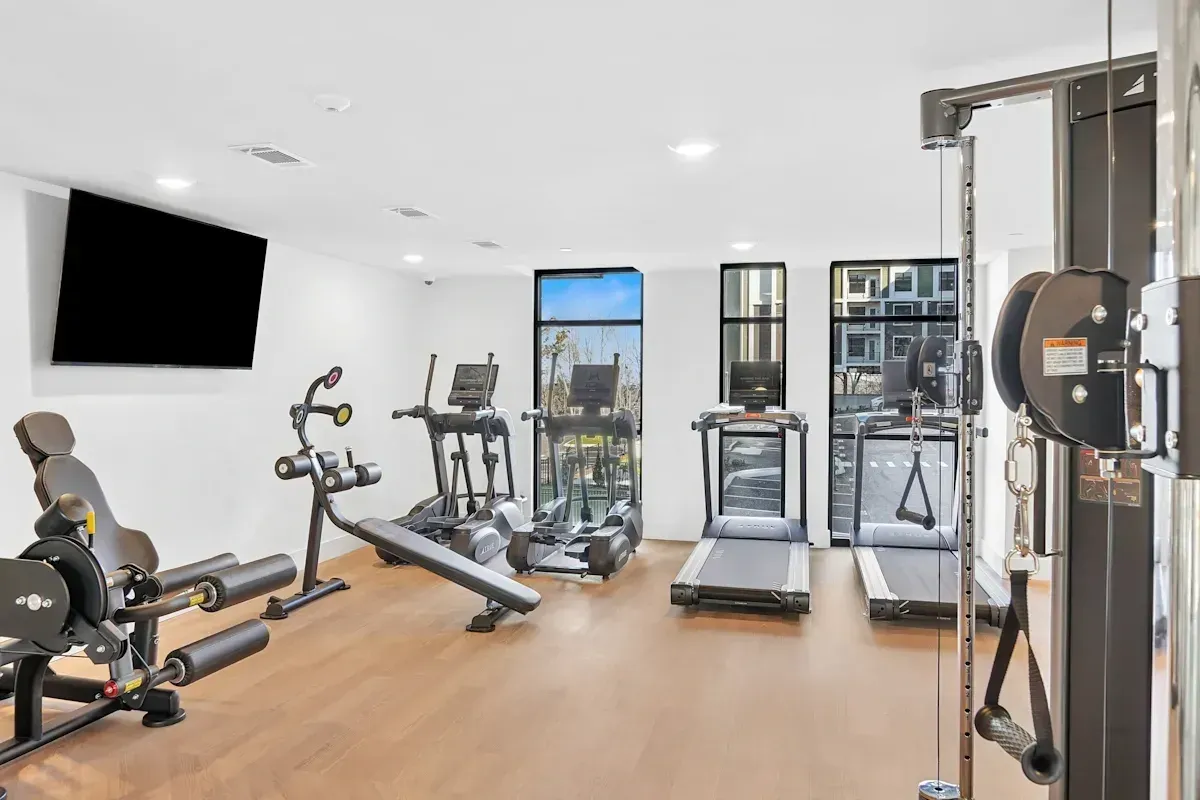 Gym with cardio machines, weight machines, and a TV.