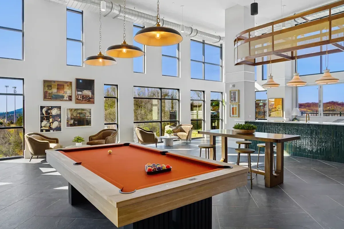 Billiard table and lounge area with large windows and high ceilings