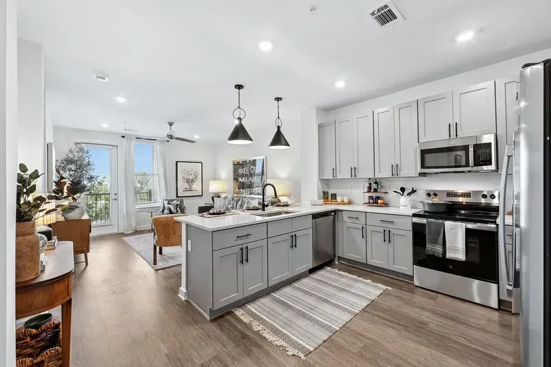 Modern kitchen with island, stainless steel appliances, and open living area.
