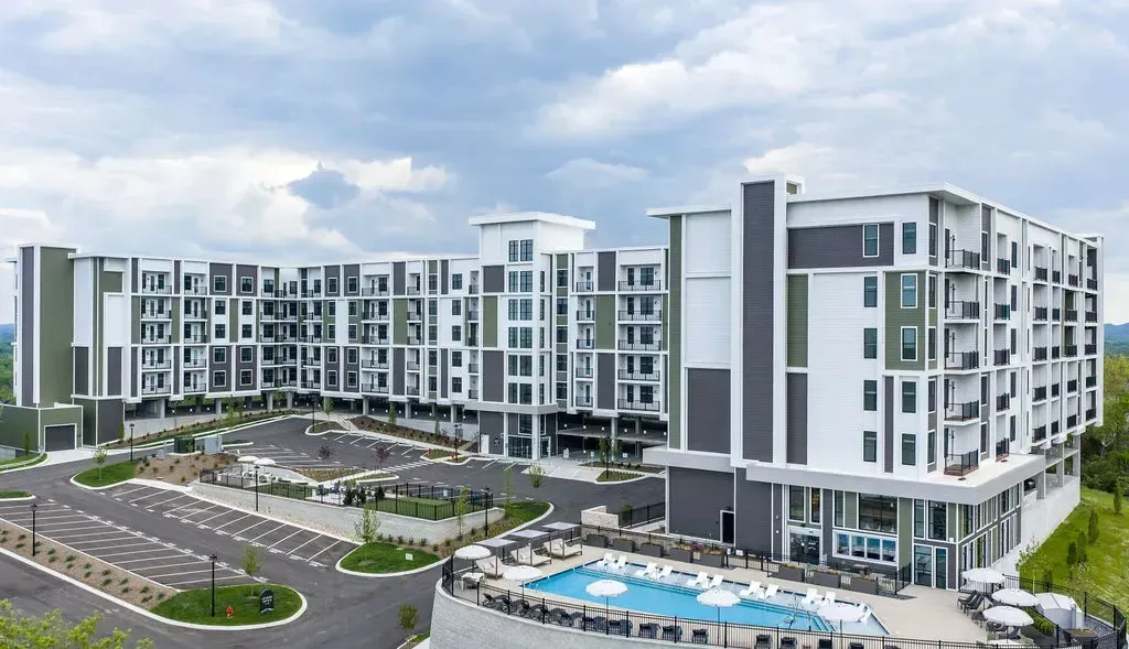 Modern apartment building exterior with a swimming pool and lounge area.
