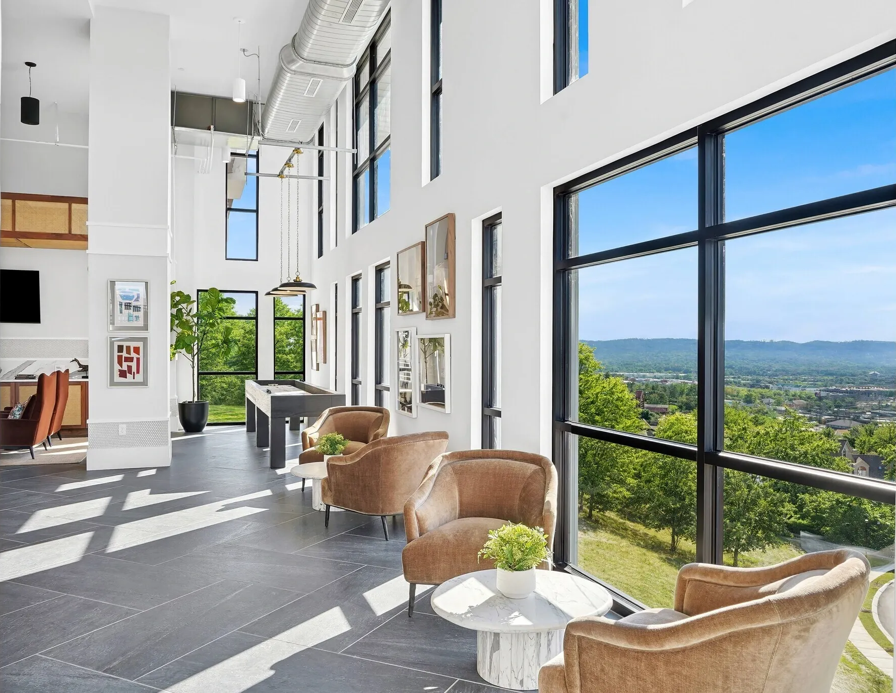 Modern indoor lounge with wicker chairs, large windows, and a scenic mountain view.