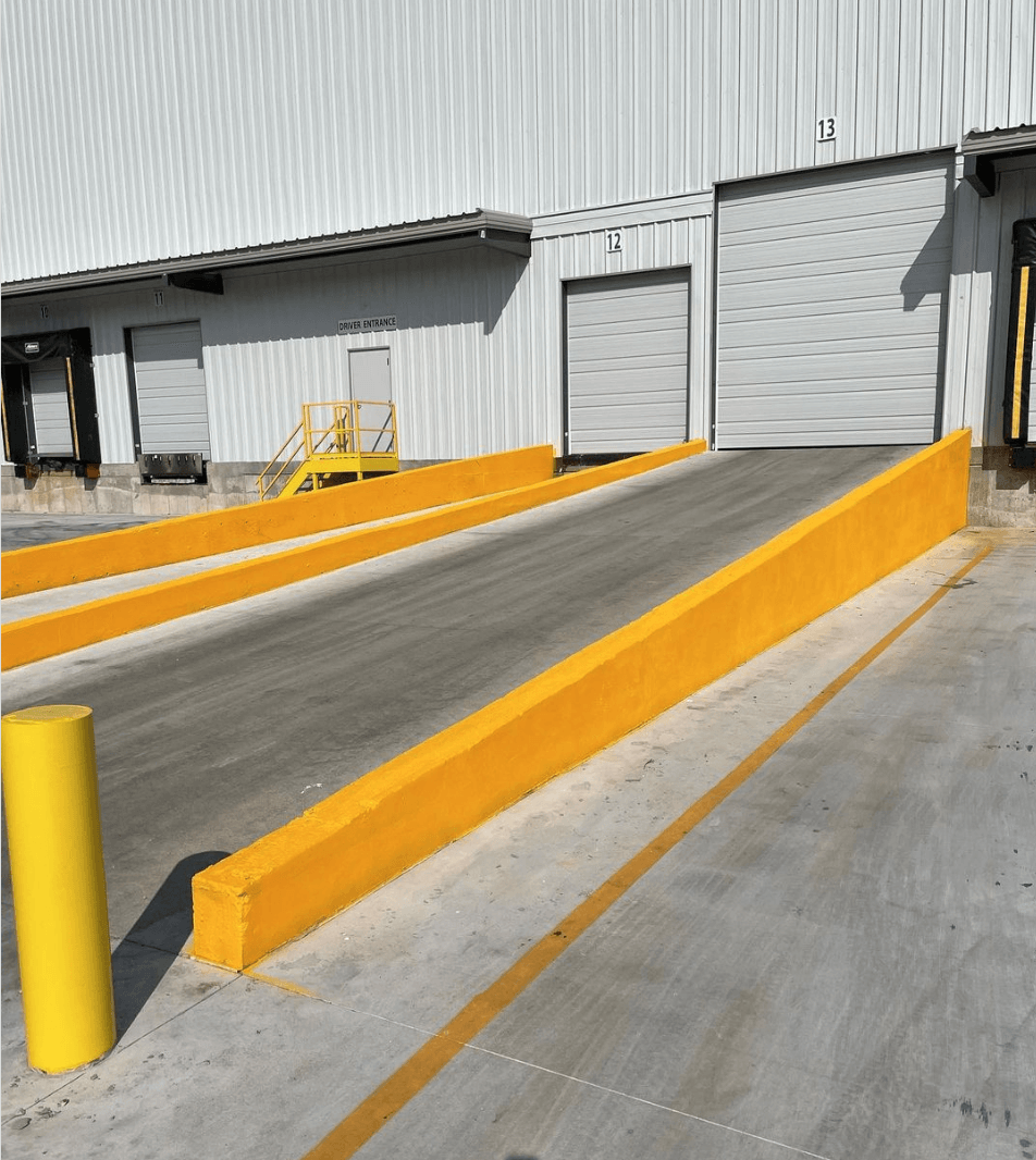 A ramp with yellow barriers and a yellow pole in front of a building