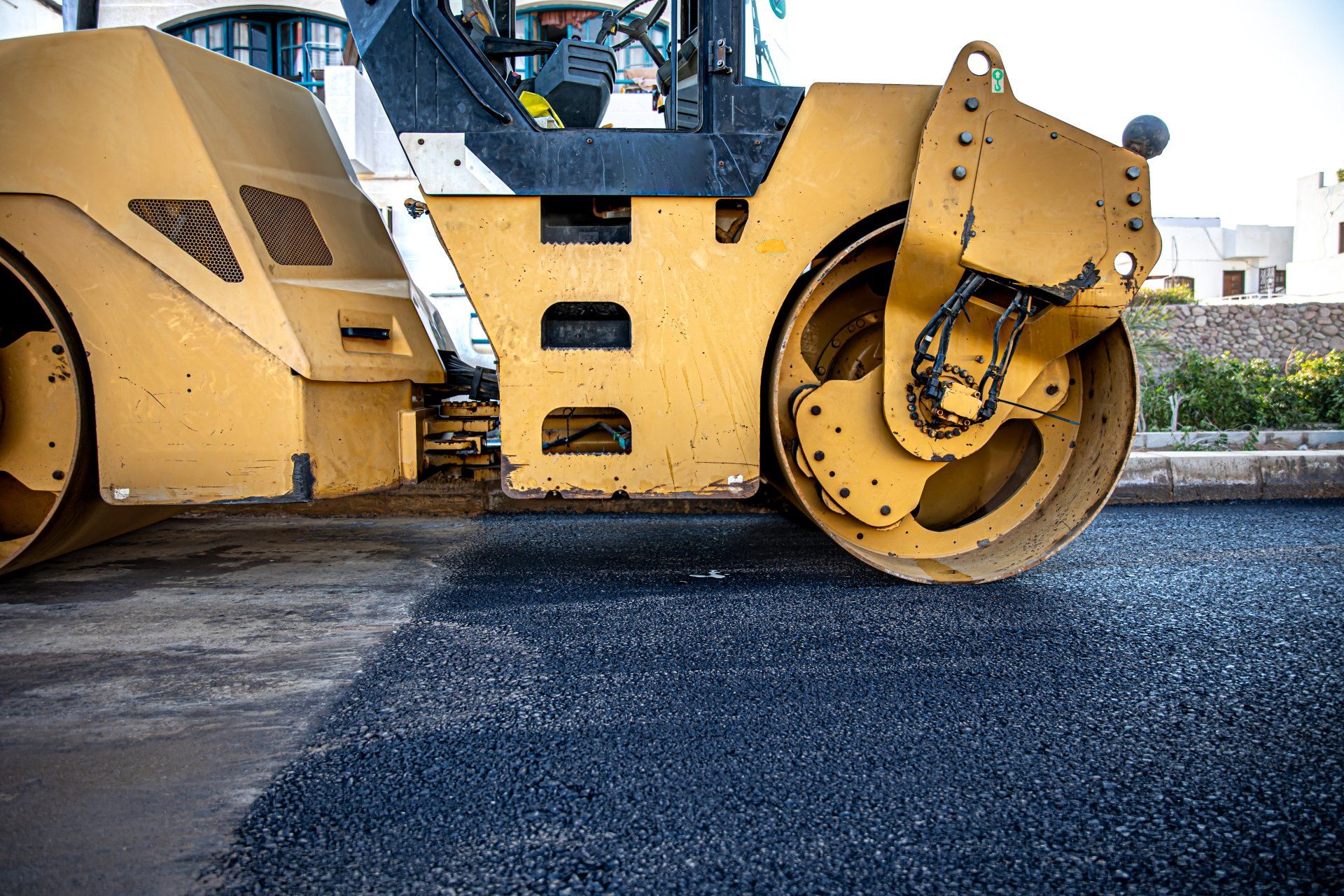 A yellow roller is rolling asphalt on a road.