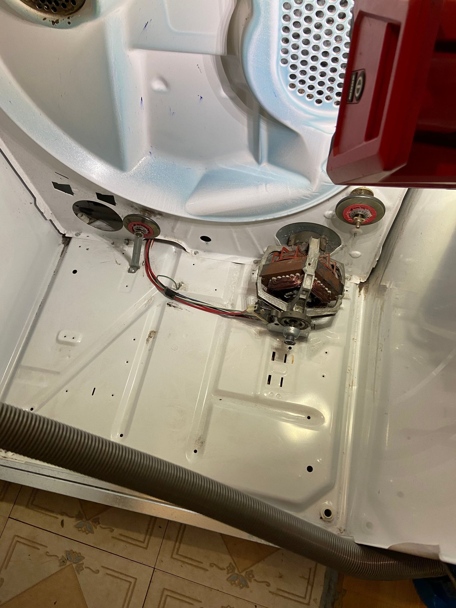 Damaged white appliance interior with exposed wiring, burnt component, and red side panel