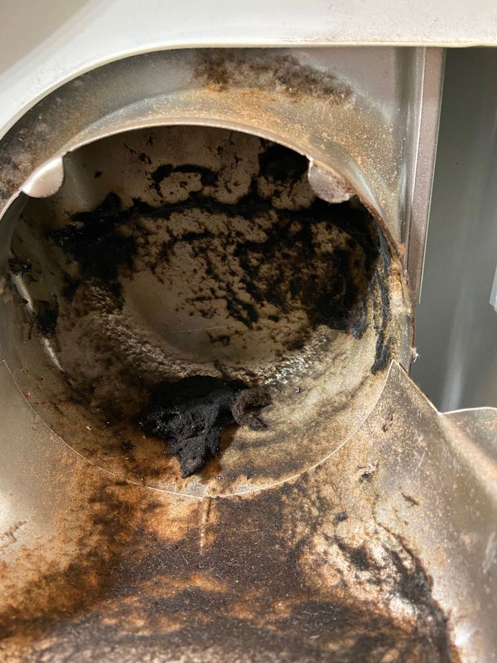 Close-up of a rusted metal pipe opening with dark grime and corrosion inside.