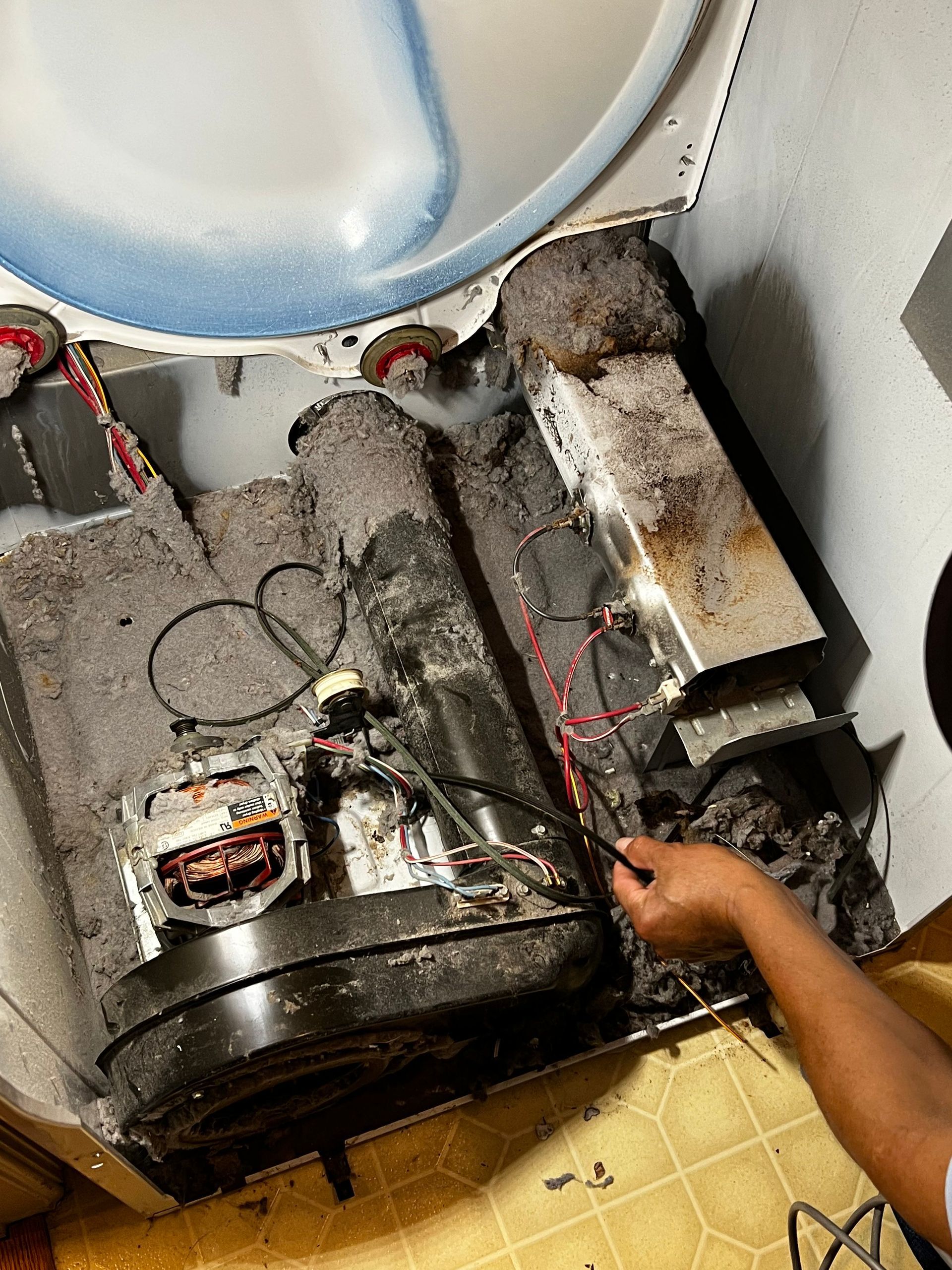 Burnt electrical equipment and wires on the floor, with a hand pointing at the damage