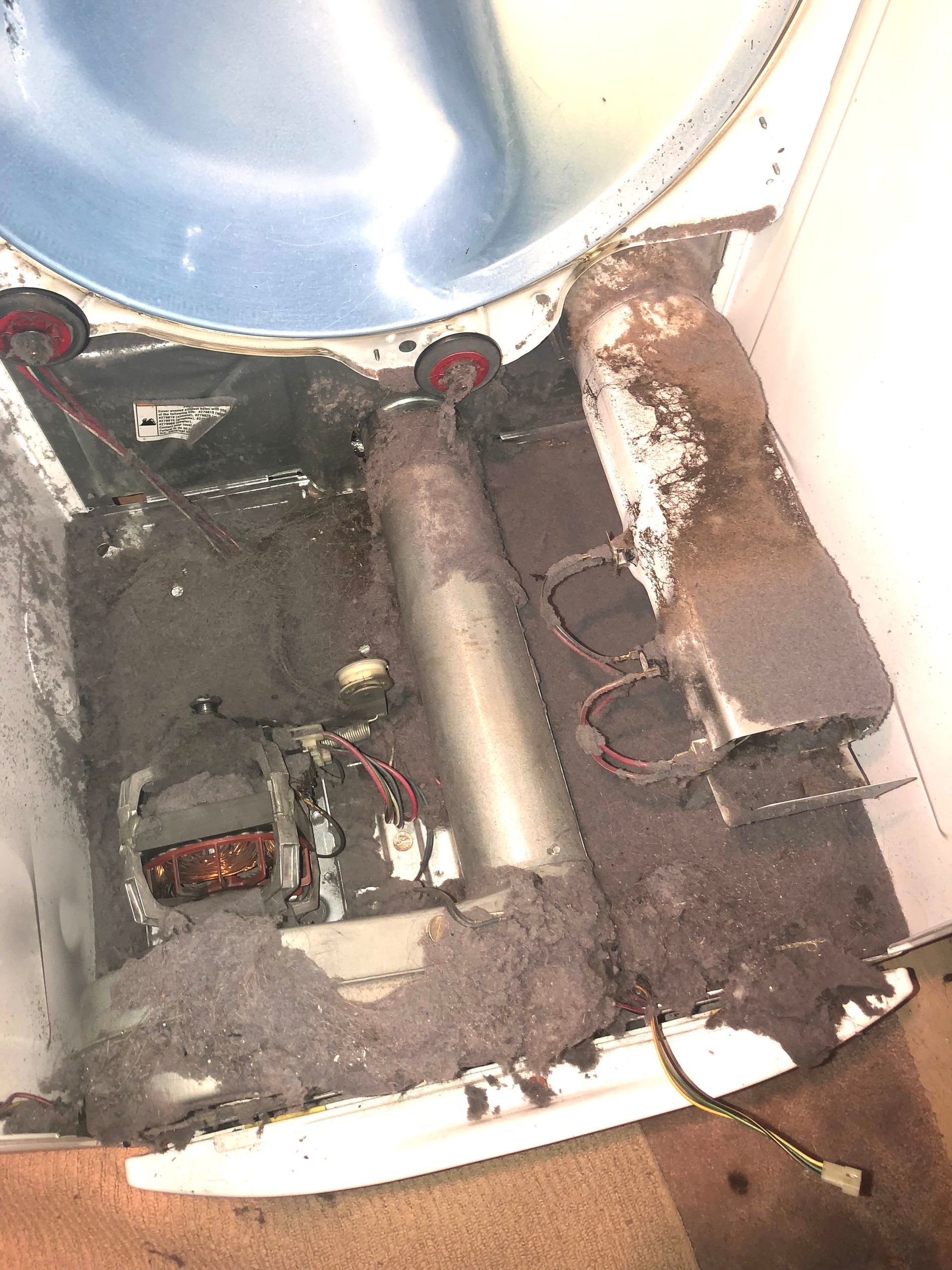 Open machine interior with dusty components, wiring, and a metal drum at the top.