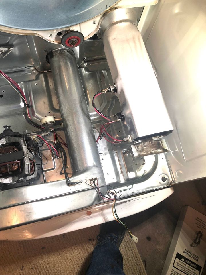 Close-up of exposed wiring and metal tubing inside a small machine compartment.