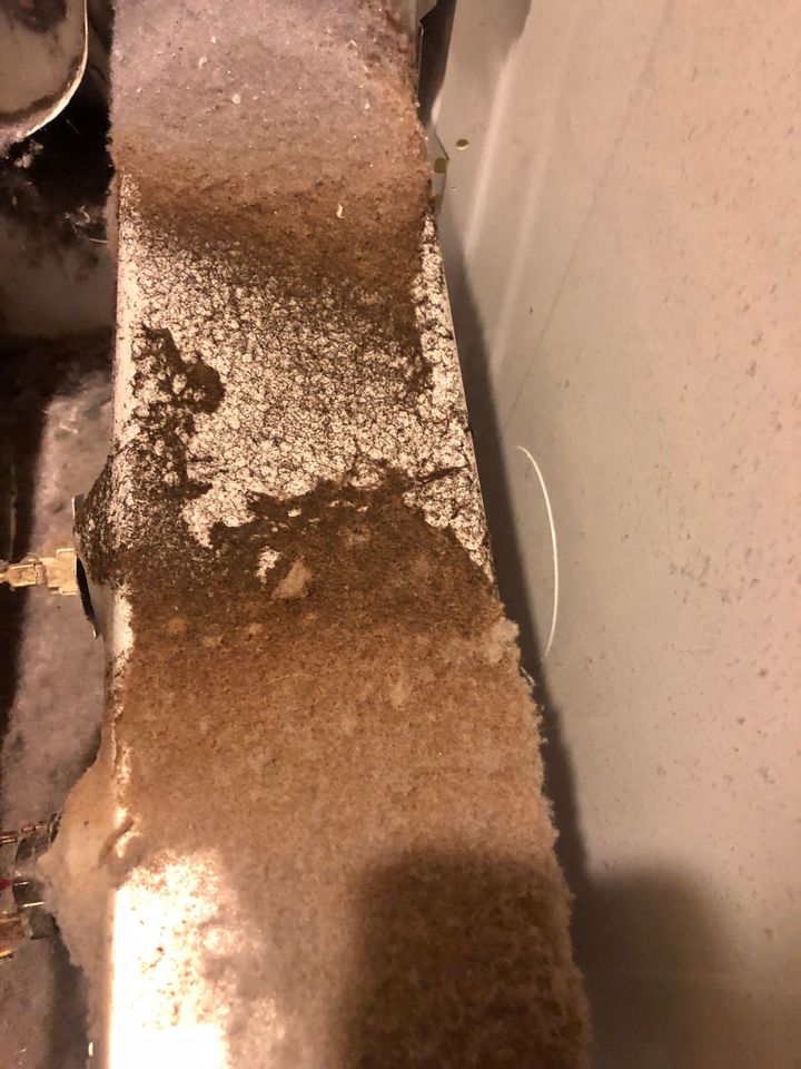 Brown carpeted stair edge with a white textured wall and a dark shadowed area beside it