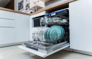 Open dishwasher in a modern kitchen, loaded with dishes and cookware