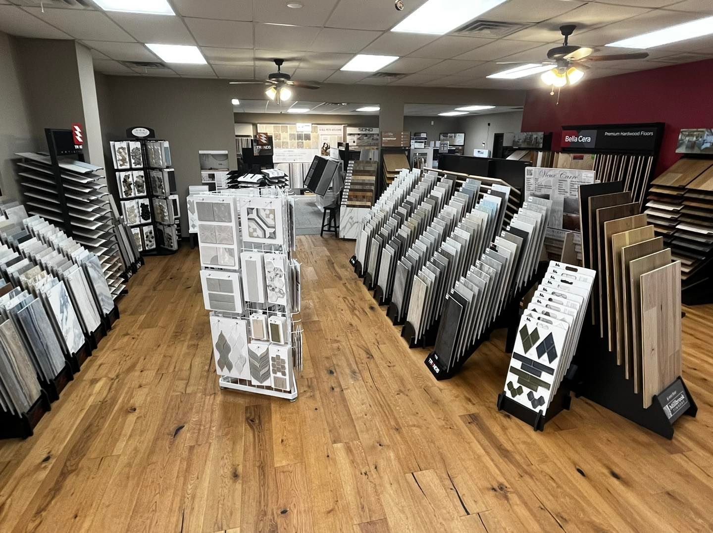 A flooring showroom featuring numerous floor sample displays and tile boards arranged on a wooden floor.