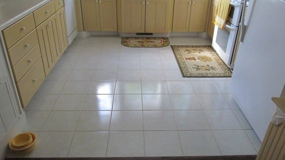 A kitchen interior with light-colored tile flooring, yellow wooden cabinets, and two patterned accent rugs.