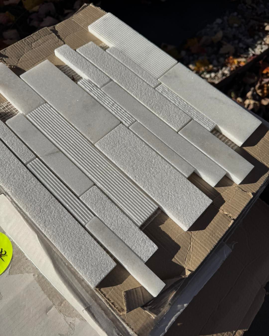 A sample tile sheet featuring a mix of white stone strips with smooth, textured, and ribbed surface finishes.