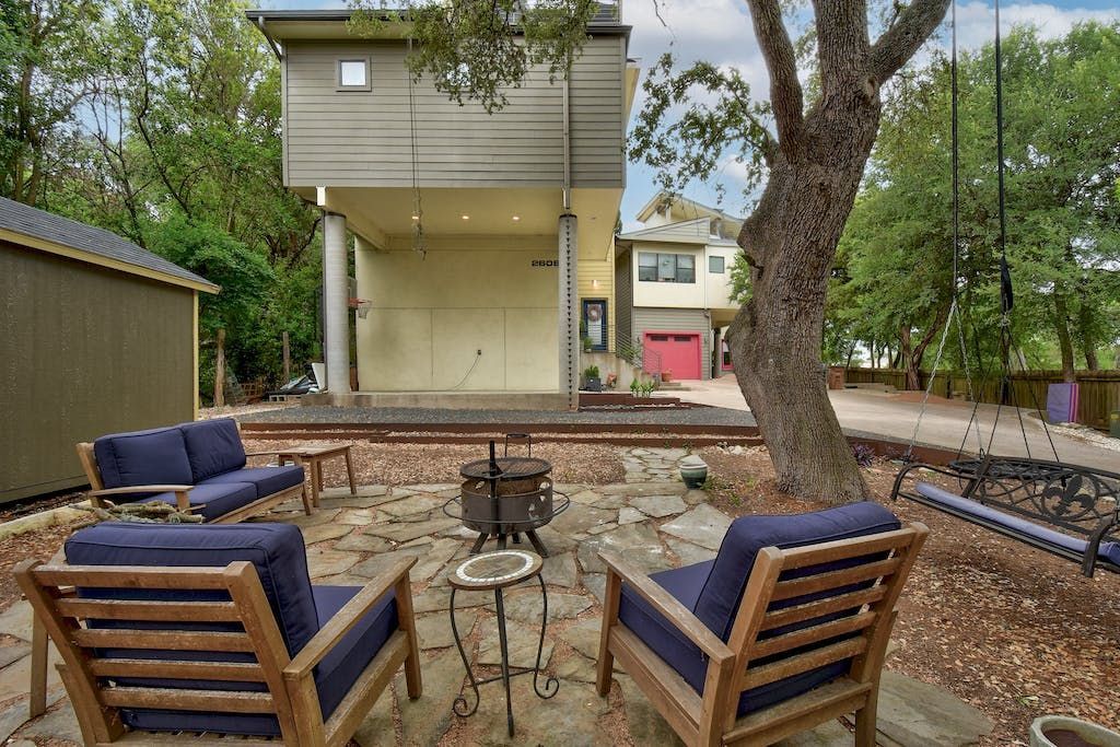A patio with chairs and a fire pit in front of a house