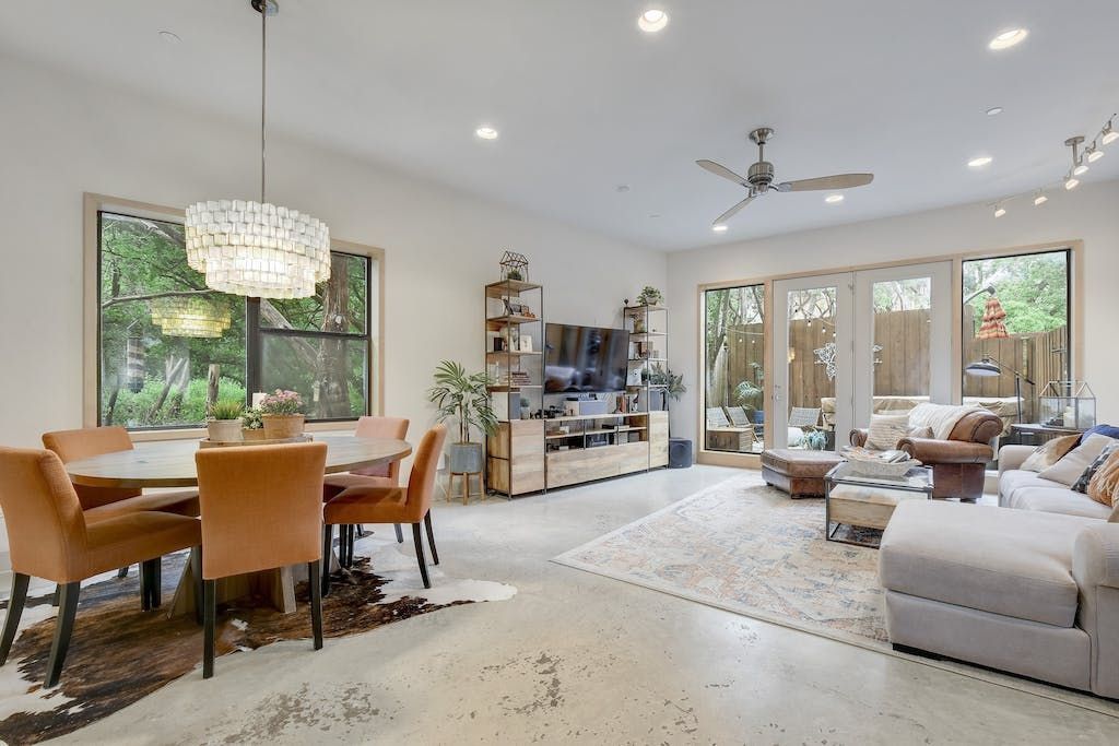 A living room with a dining table and chairs and a ceiling fan.