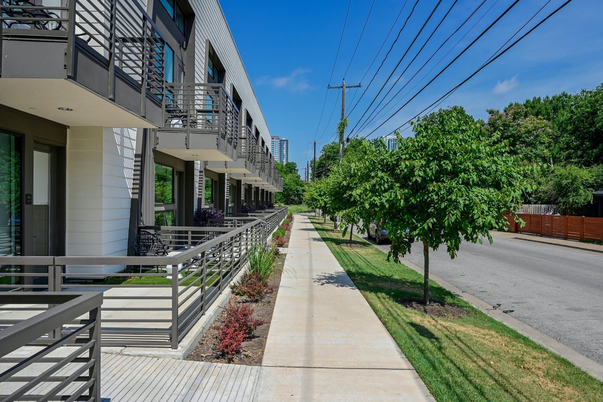 A sidewalk leading to a building with balconies on a sunny day.