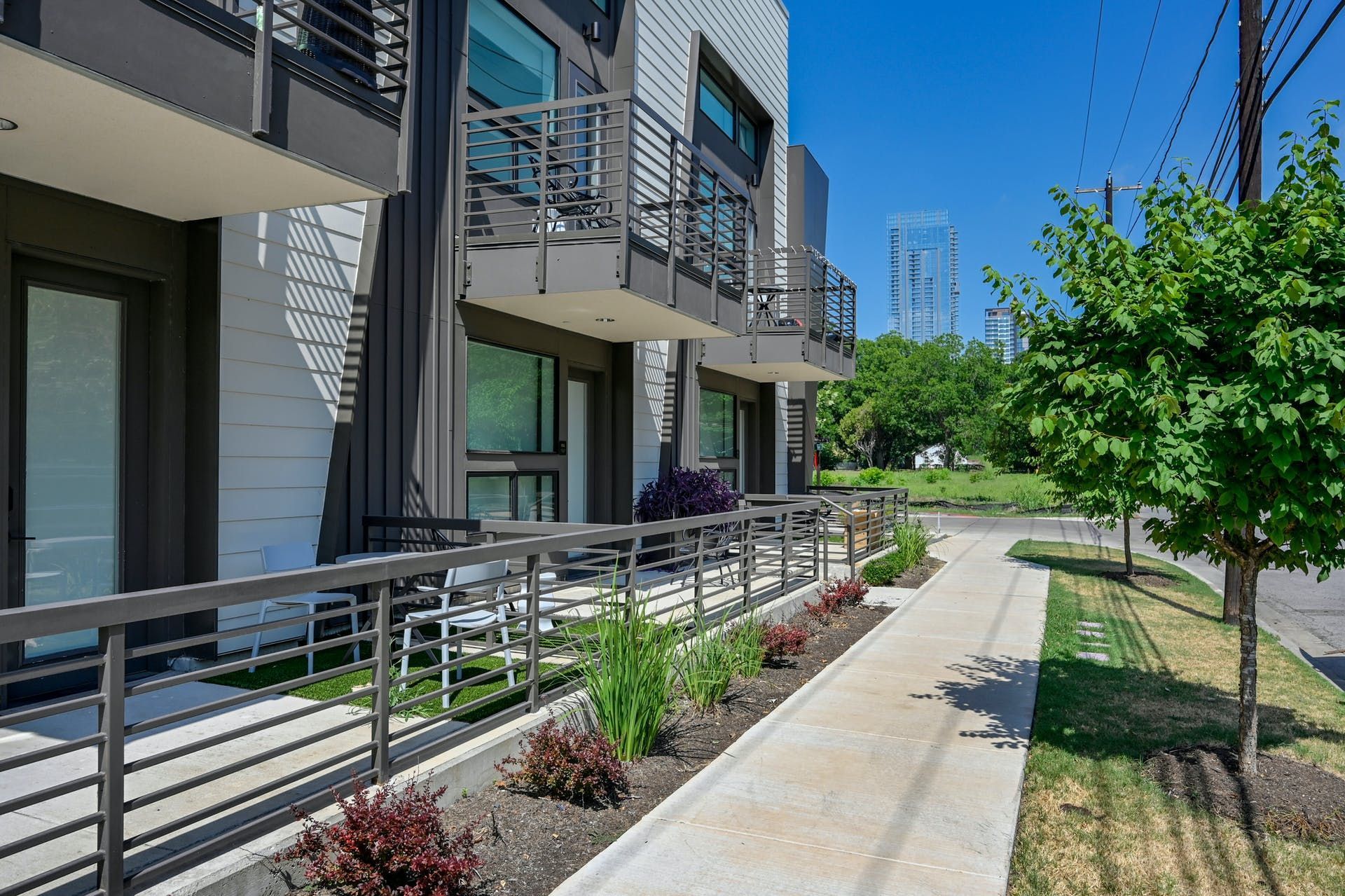 A sidewalk leading to a building with balconies and a fence.