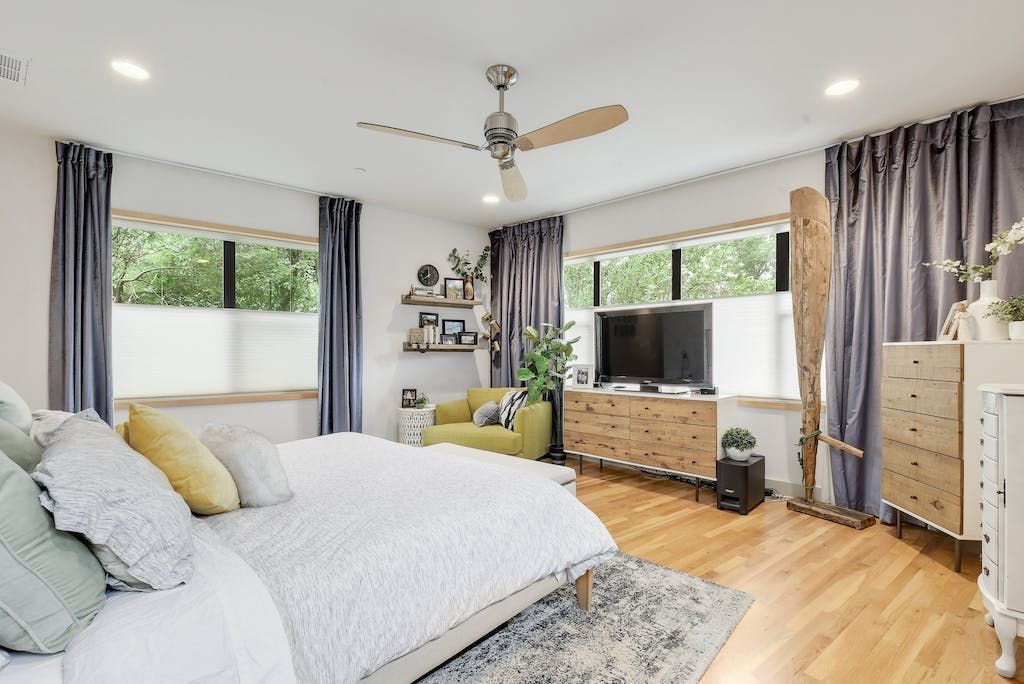 A bedroom with a bed , dresser , chair , television and ceiling fan.