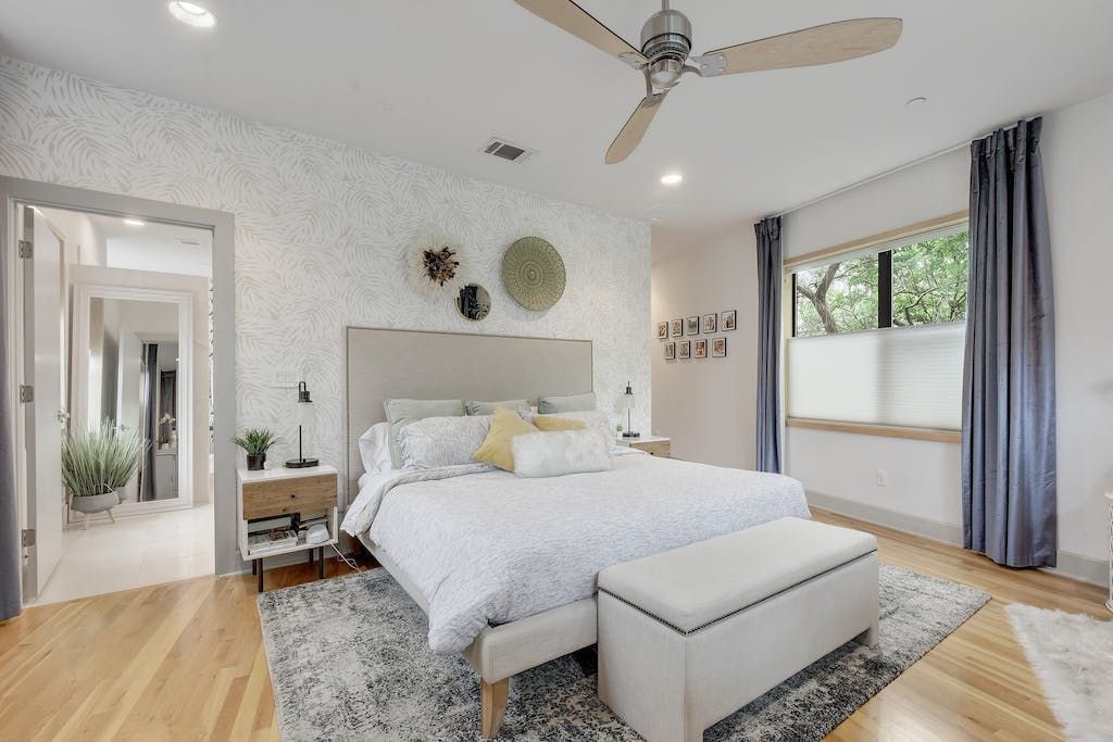 A bedroom with a large bed and a ceiling fan.