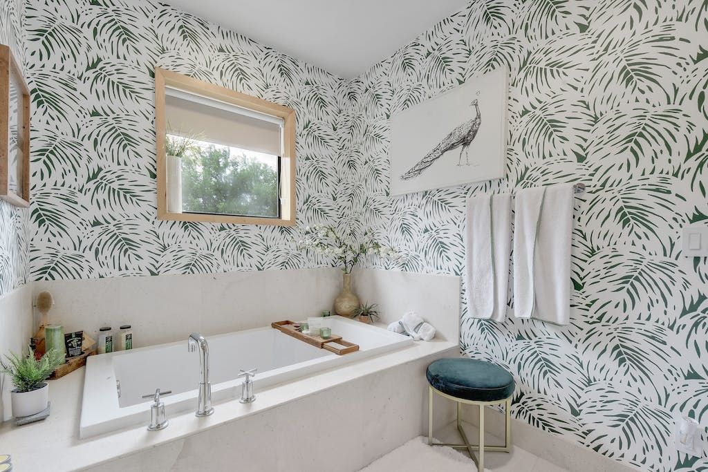 A bathroom with a bathtub , mirror , and stool.