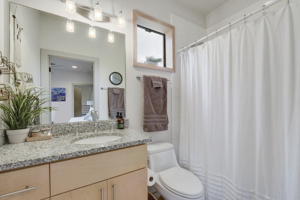 A bathroom with a toilet , sink , mirror and shower curtain.