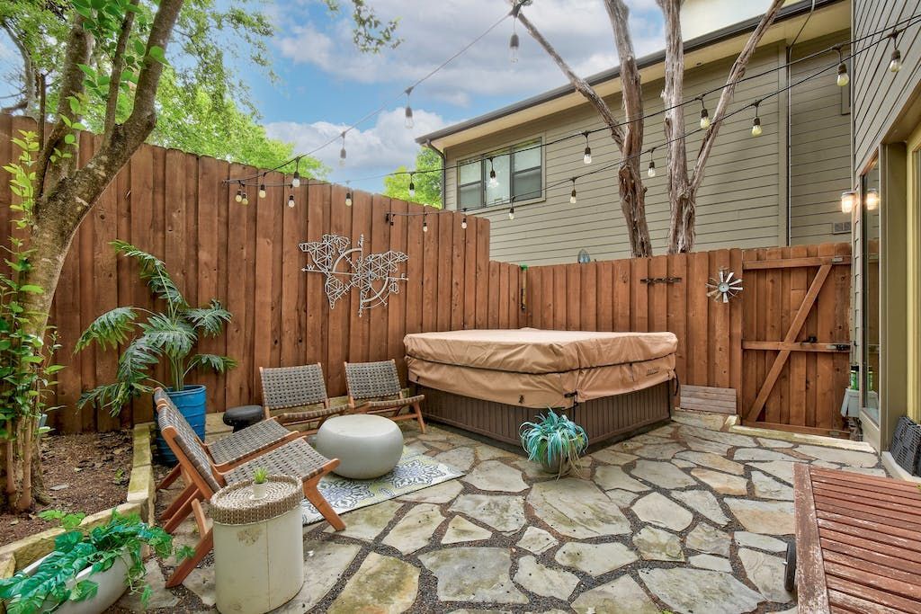 A backyard with a hot tub and a wooden fence.