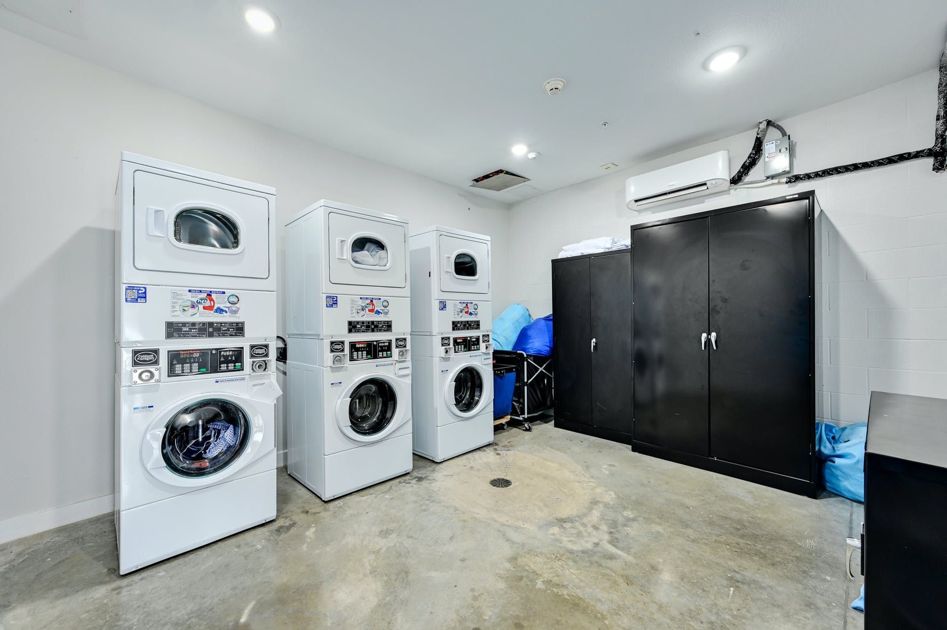 A laundry room with a lot of washers and dryers stacked on top of each other.