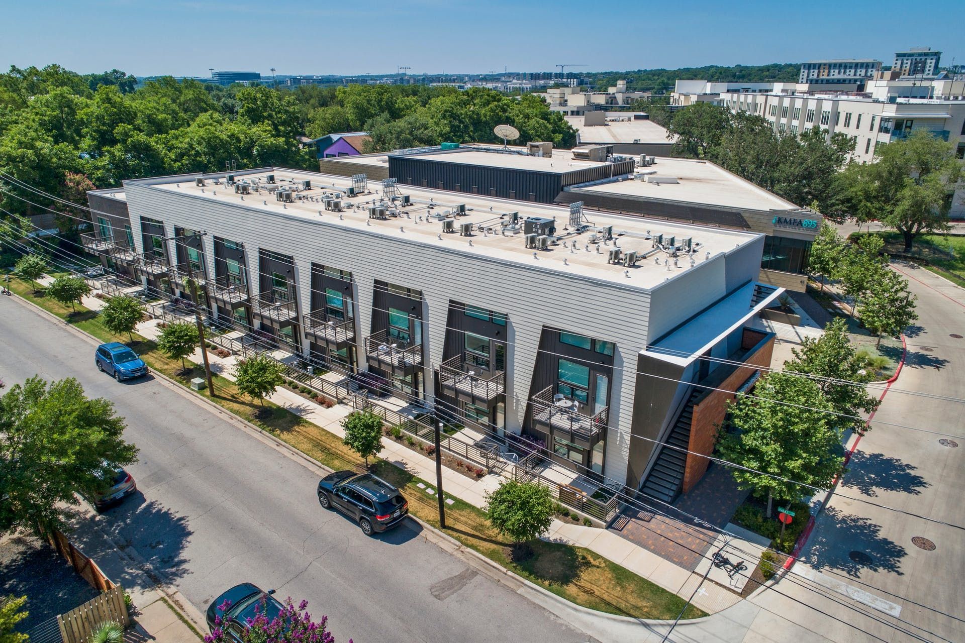 An aerial view of a large building surrounded by trees and a street.
