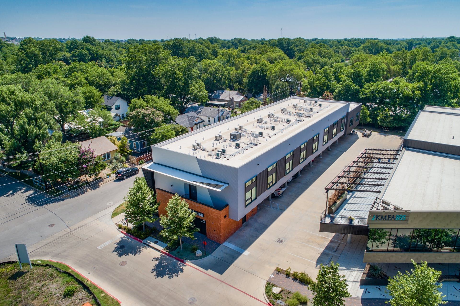 An aerial view of a large building with a lot of windows surrounded by trees.