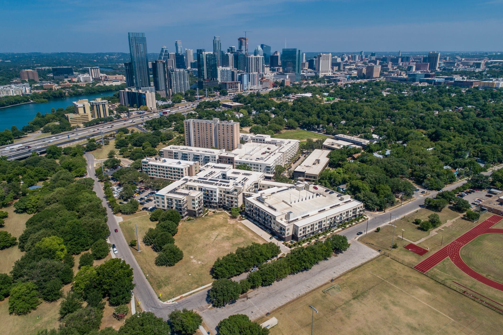 An aerial view of a city with a park in the foreground and a city skyline in the background.