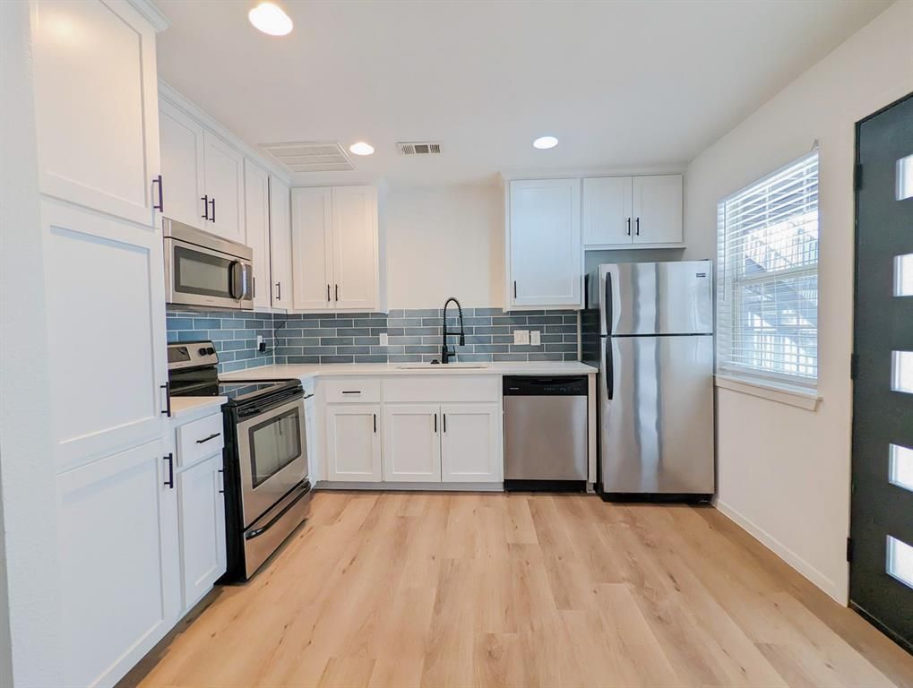 A kitchen with stainless steel appliances and white cabinets